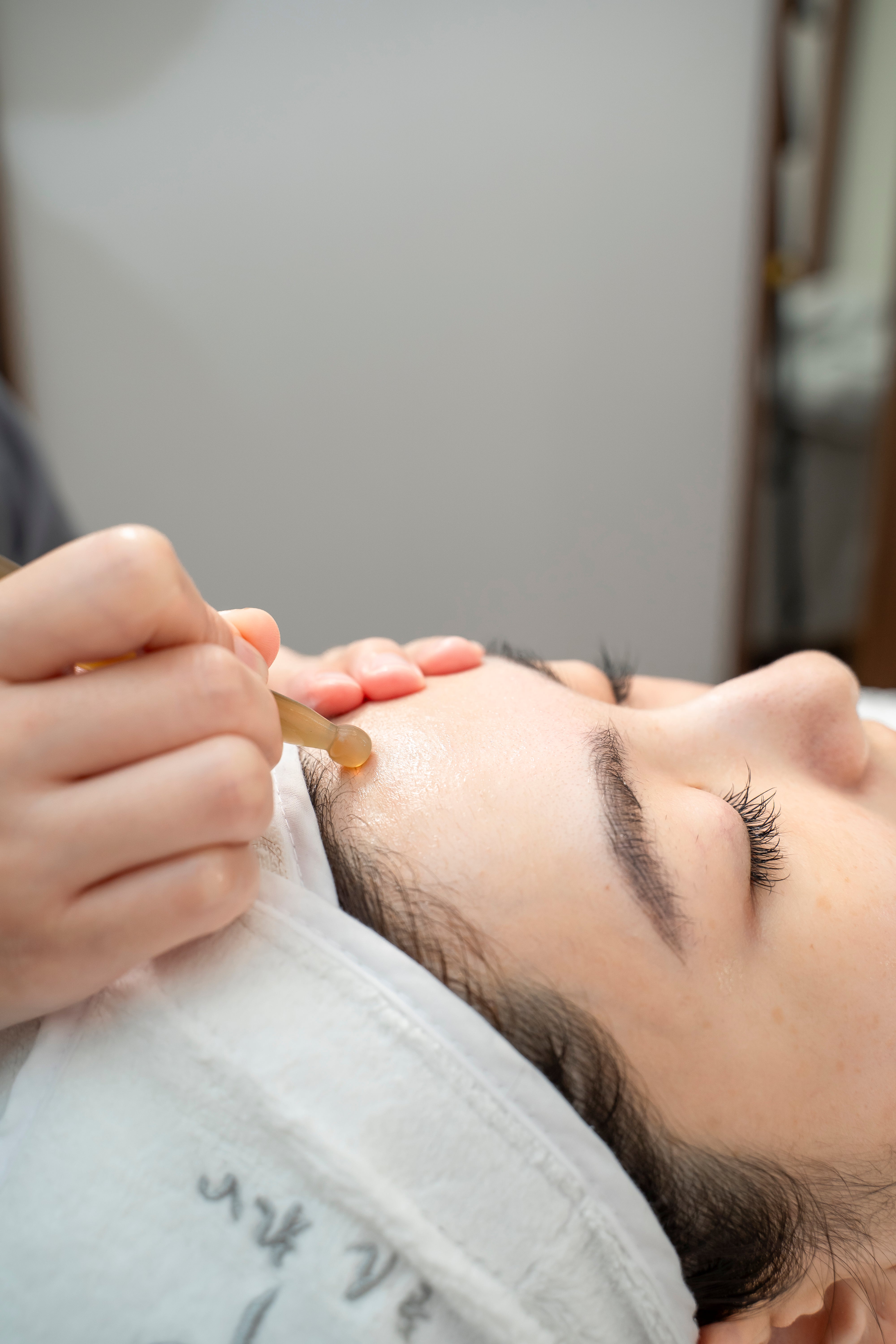 Person receiving a facial treatment with a dropper at a spa.