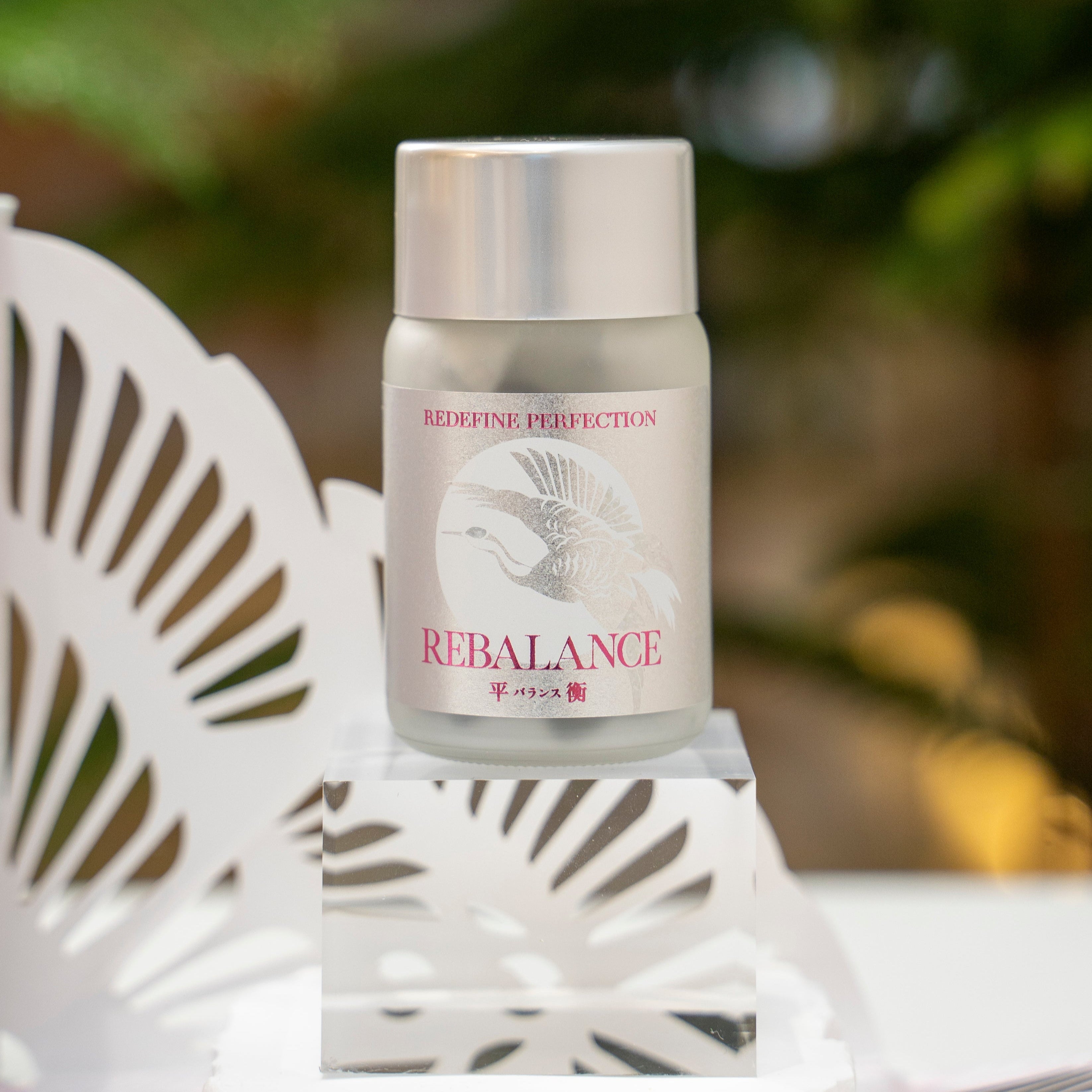 Skincare product labeled 'Rebalance' on a decorative stand with a blurred green background