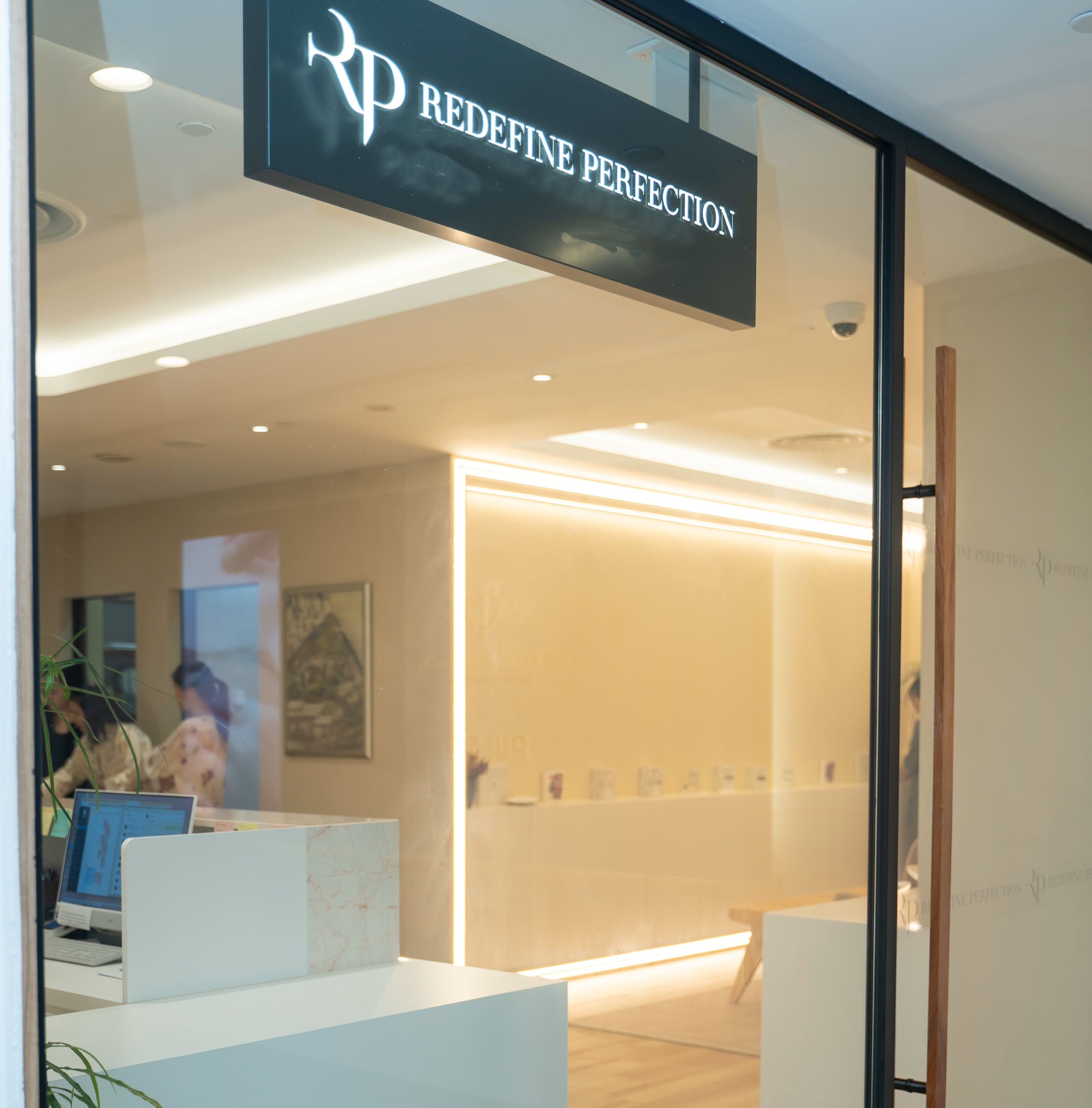 Interior of a modern office with reception desk and 'Redefine Perfection' sign.