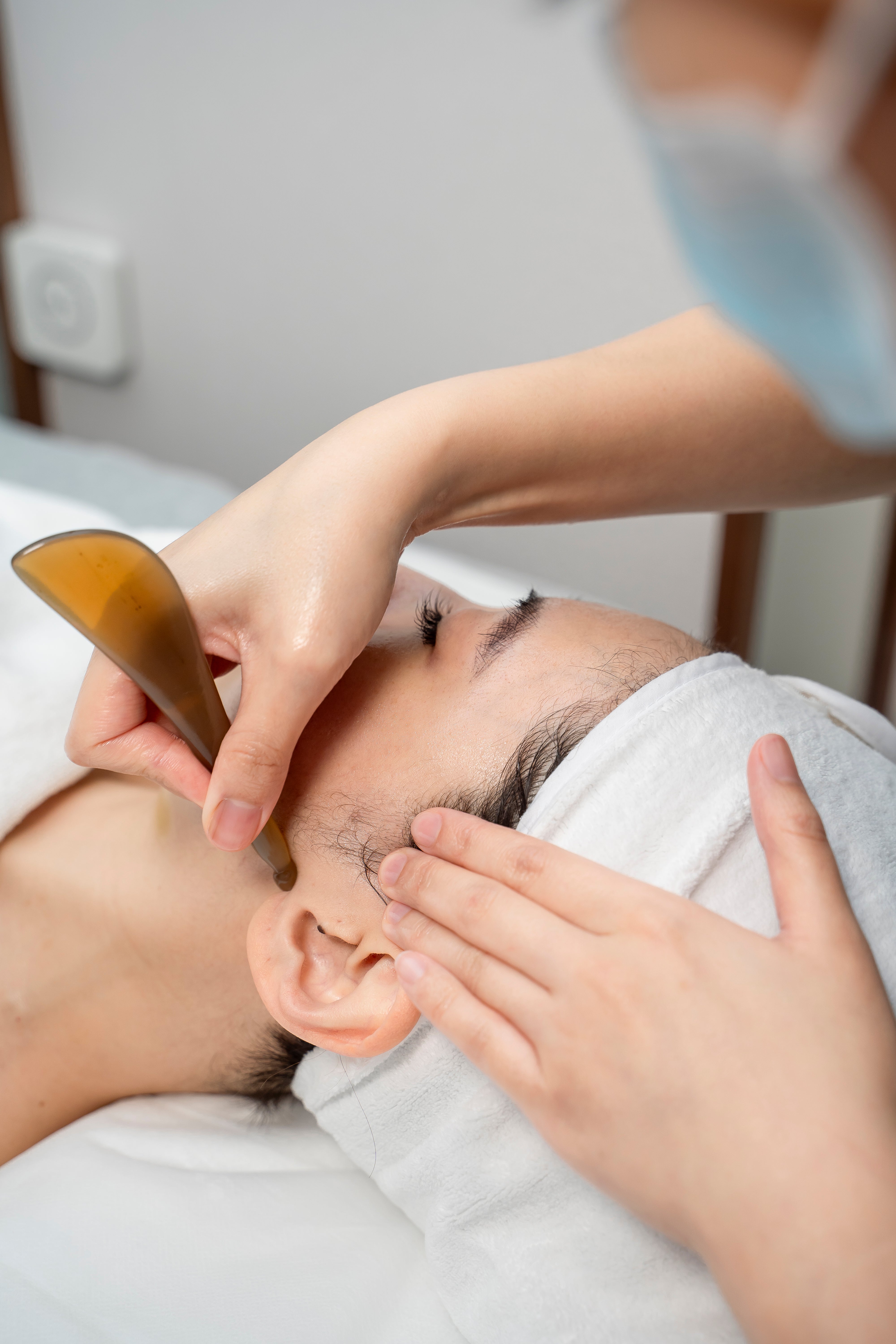 Person receiving a bo-jin facial treatment with a wooden tool.