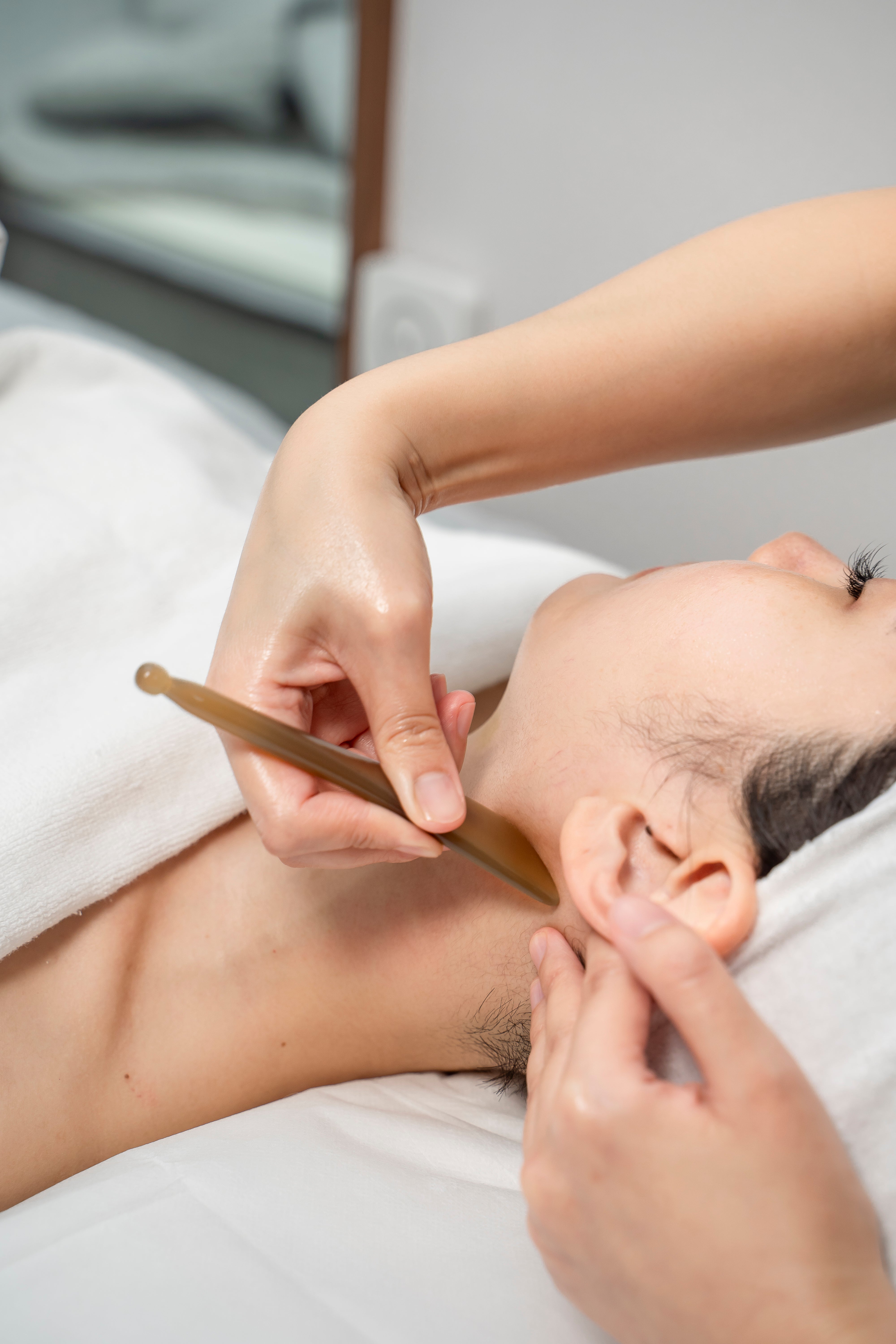 Person receiving a traditional ear massage treatment with a wooden tool.