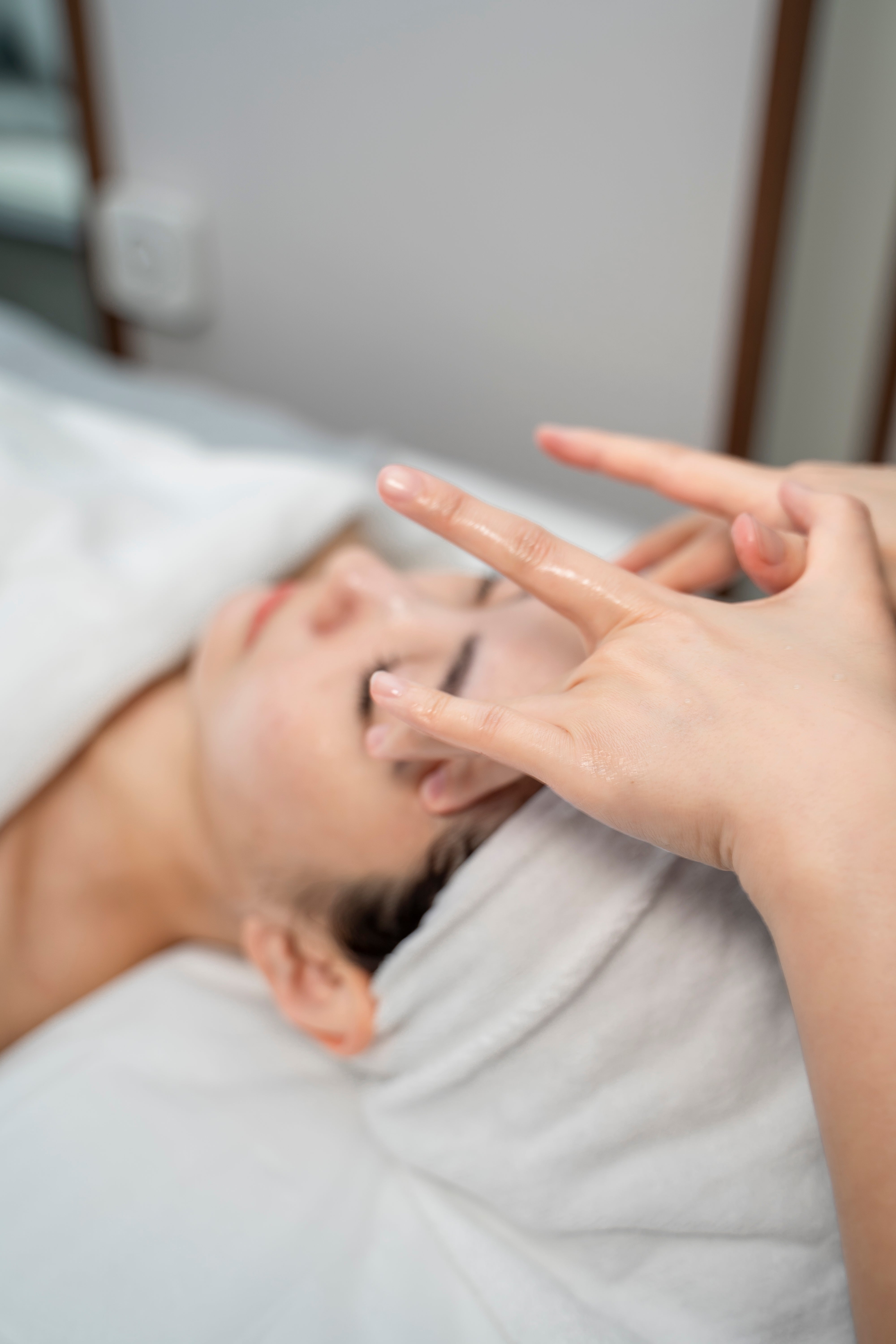 Person receiving a facial treatment with a hand touching their face.
